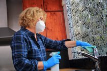 La vita quotidiana durante l'epidemia di Coronavirus, donna che pulisce la casa in maschera — Foto stock