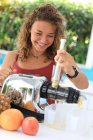 Mujer joven usando un extractor de jugo - foto de stock