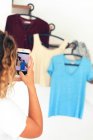 Jovem adolescente em casa com um smartphone usando o aplicativo Vinted para vender suas roupas — Fotografia de Stock
