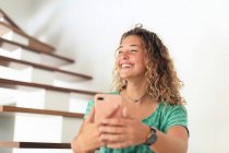 Adolescente joven en casa con un teléfono inteligente - foto de stock