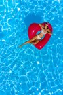 Молодая женщина у бассейна с красным буем в форме сердца — стоковое фото