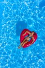 Mujer joven en la piscina con una boya roja en forma de corazón - foto de stock