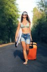 Ragazza con una valigia. Giovane e bella hippie su una strada deserta — Foto stock