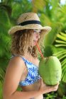 Portrait of an exotic girl drinking from a coconut — Stock Photo