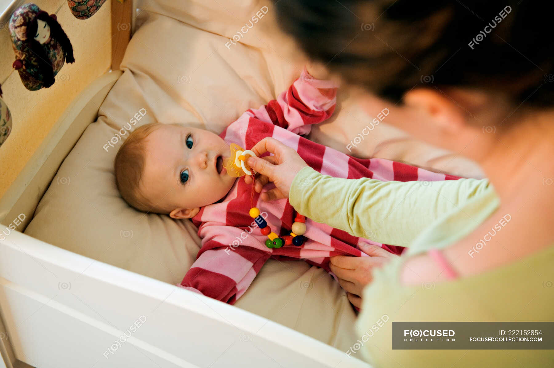 Mother giving comforter to her baby in bed — Hand, object Stock Photo 222152854