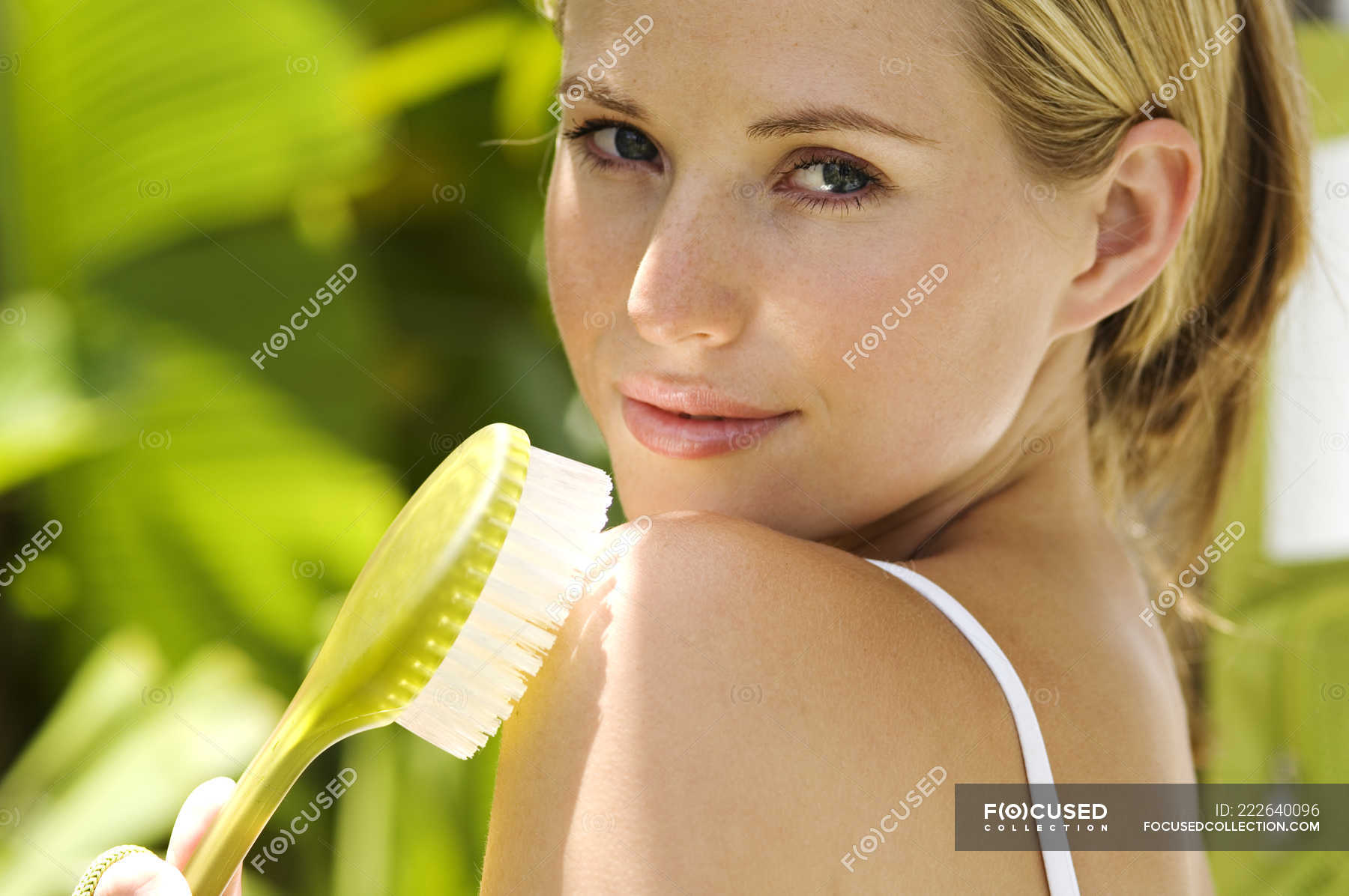 Portrait of young woman brushing shoulder outdoors — sunlight