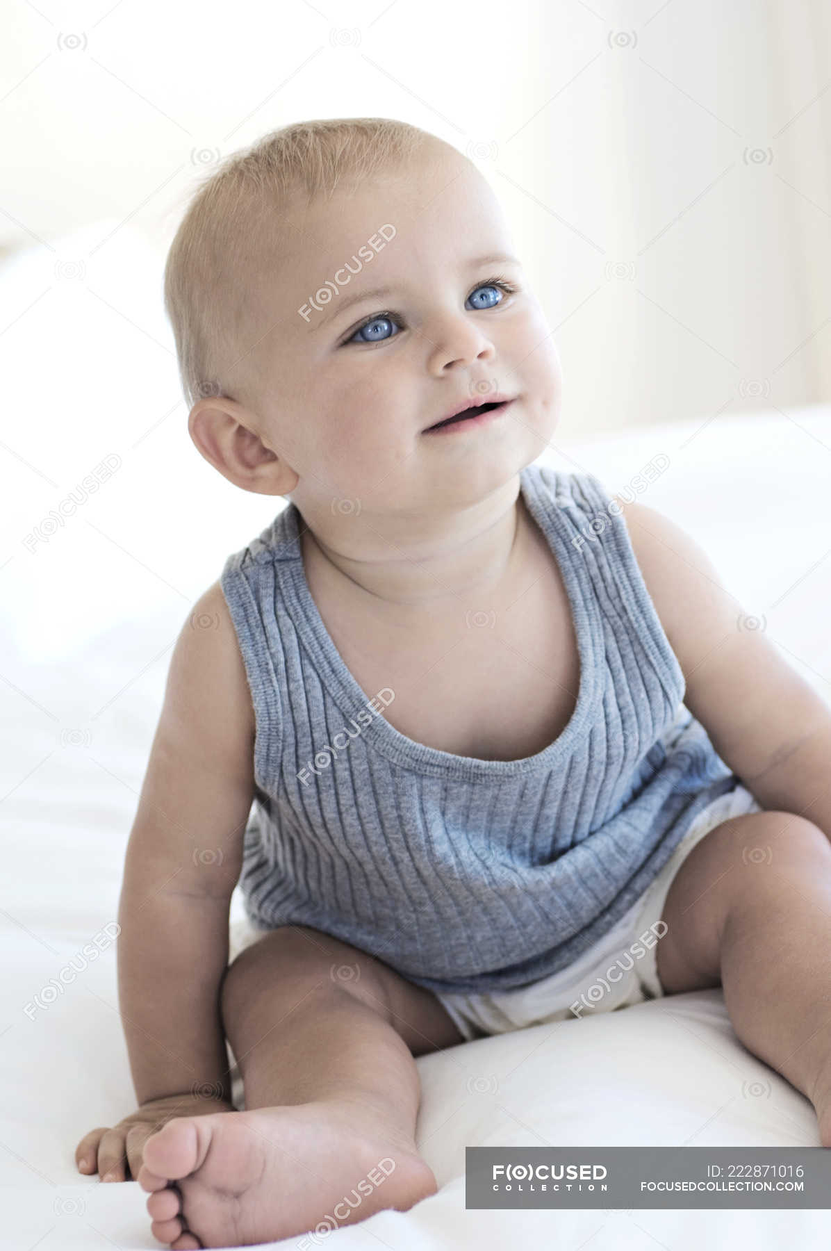 Cute Baby Boy With Blue Eyes Sitting On Bed Human Face Looking