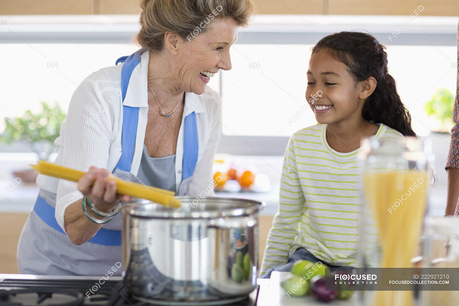 Happy senior woman with granddaughter preparing food in kitchen ...