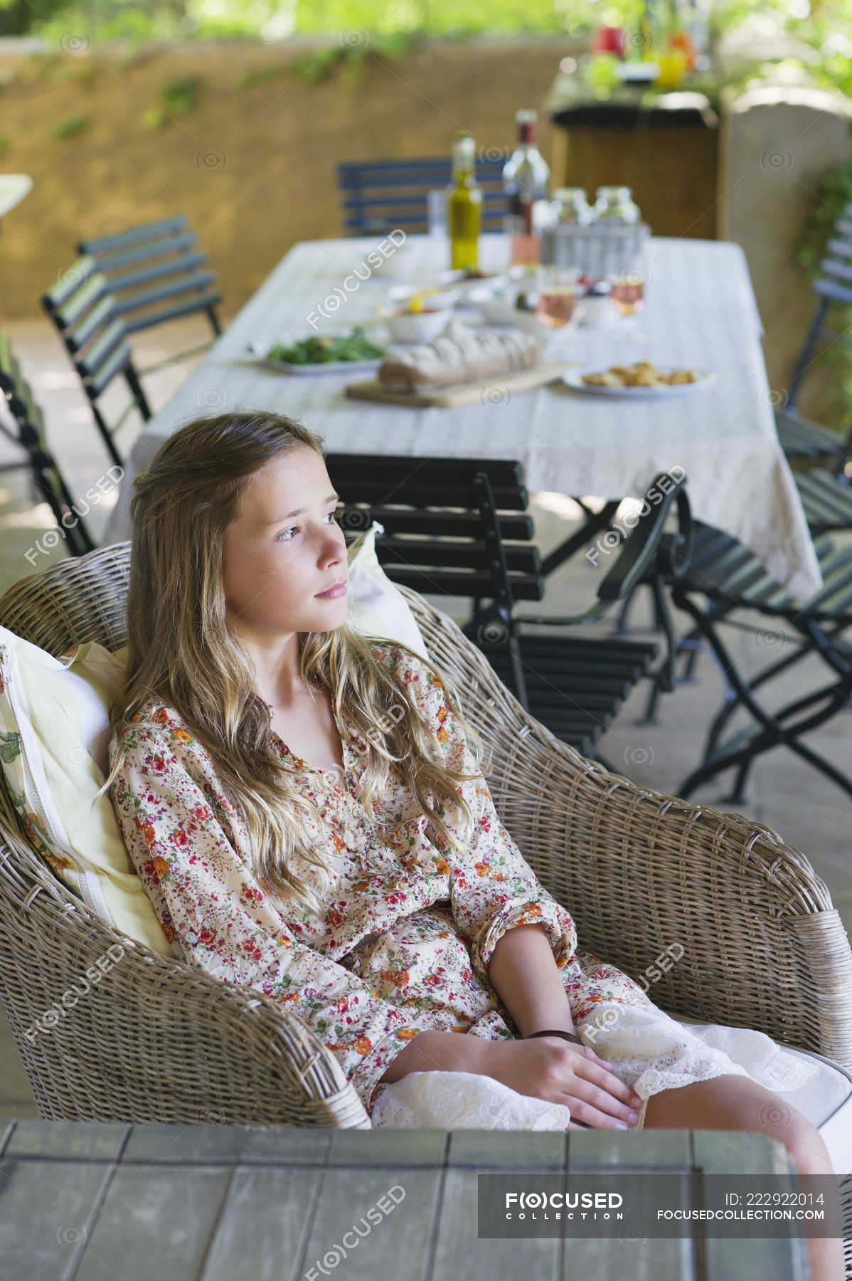 Little girl sitting and looking away with food on table on background ...