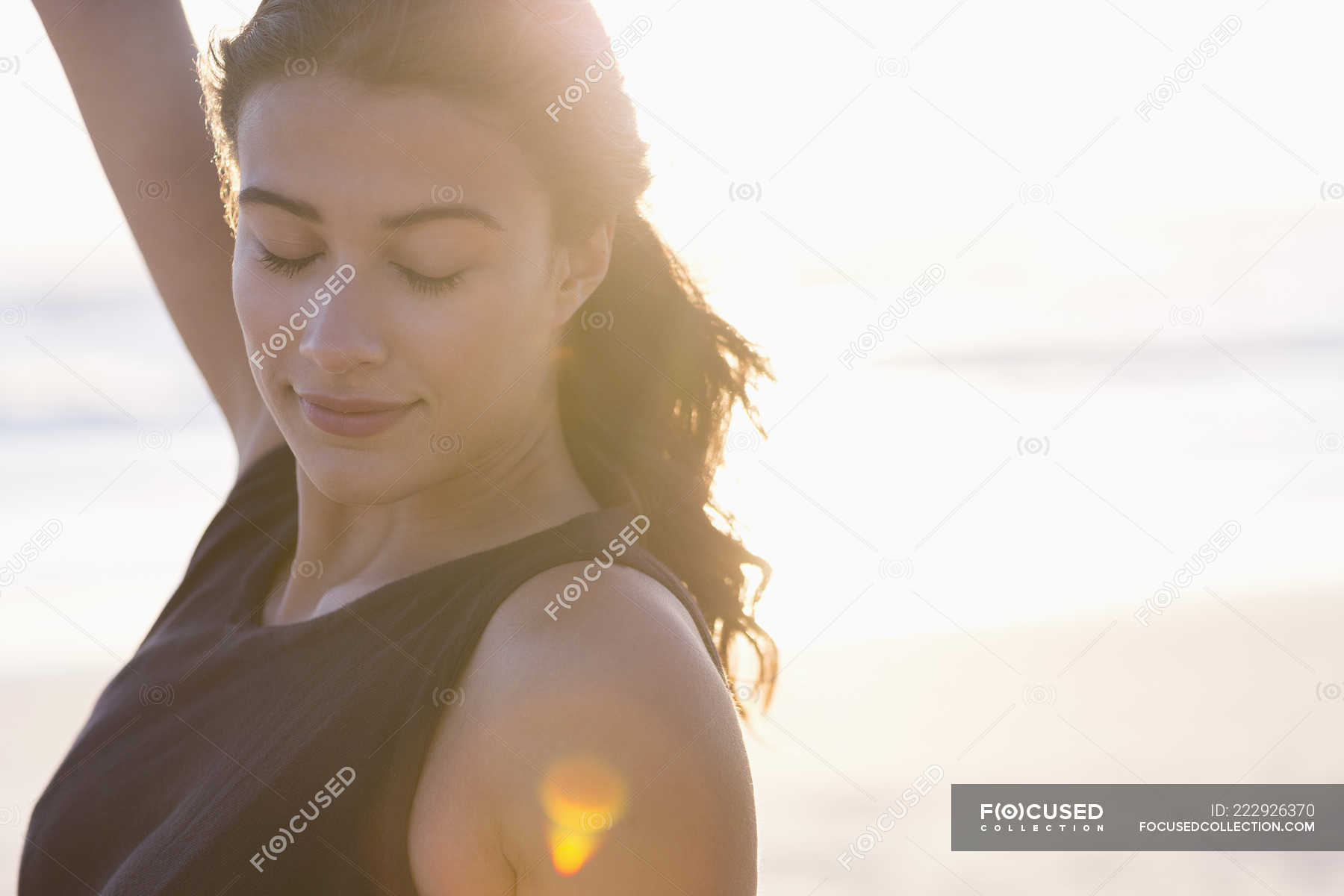 Smiling young woman standing on beach in sunlight — atmosphere, Front ...