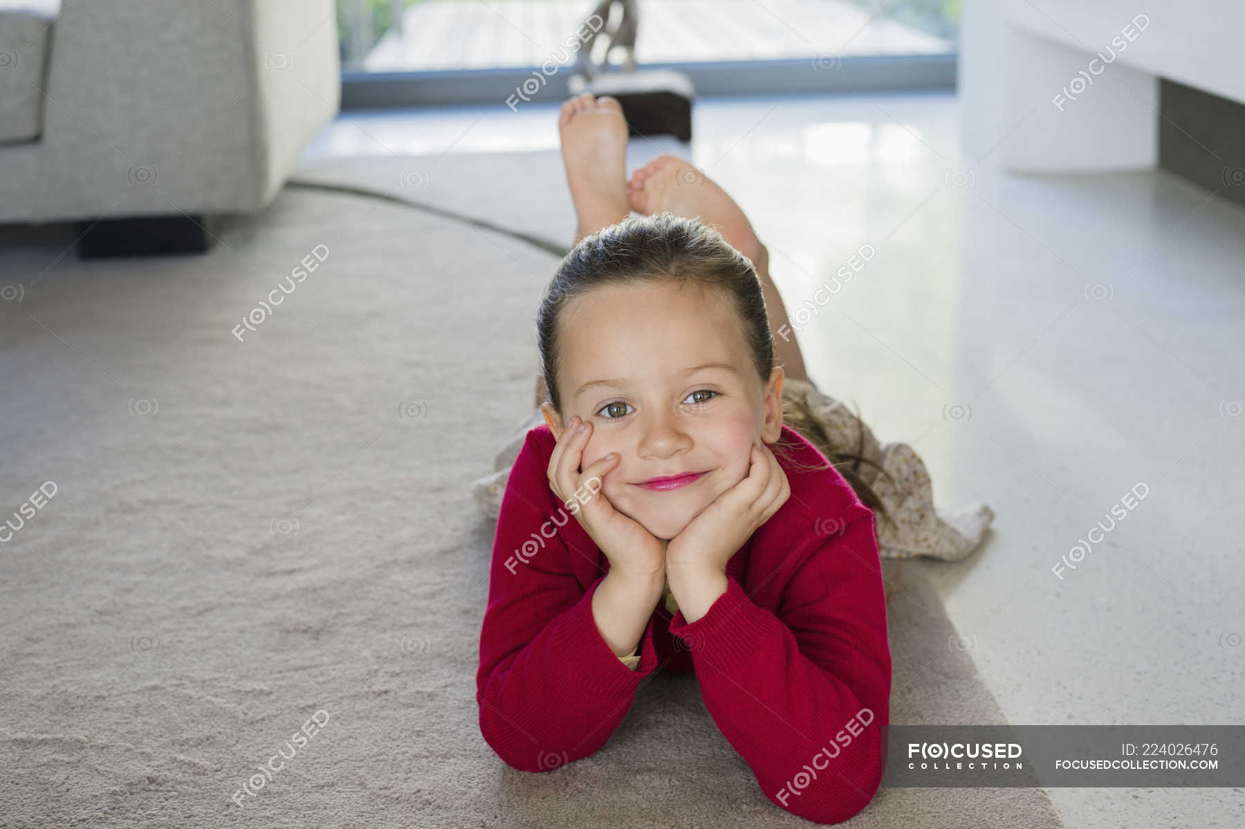Portrait Of Smiling Little Girl Lying On Carpet At Home — Childhood