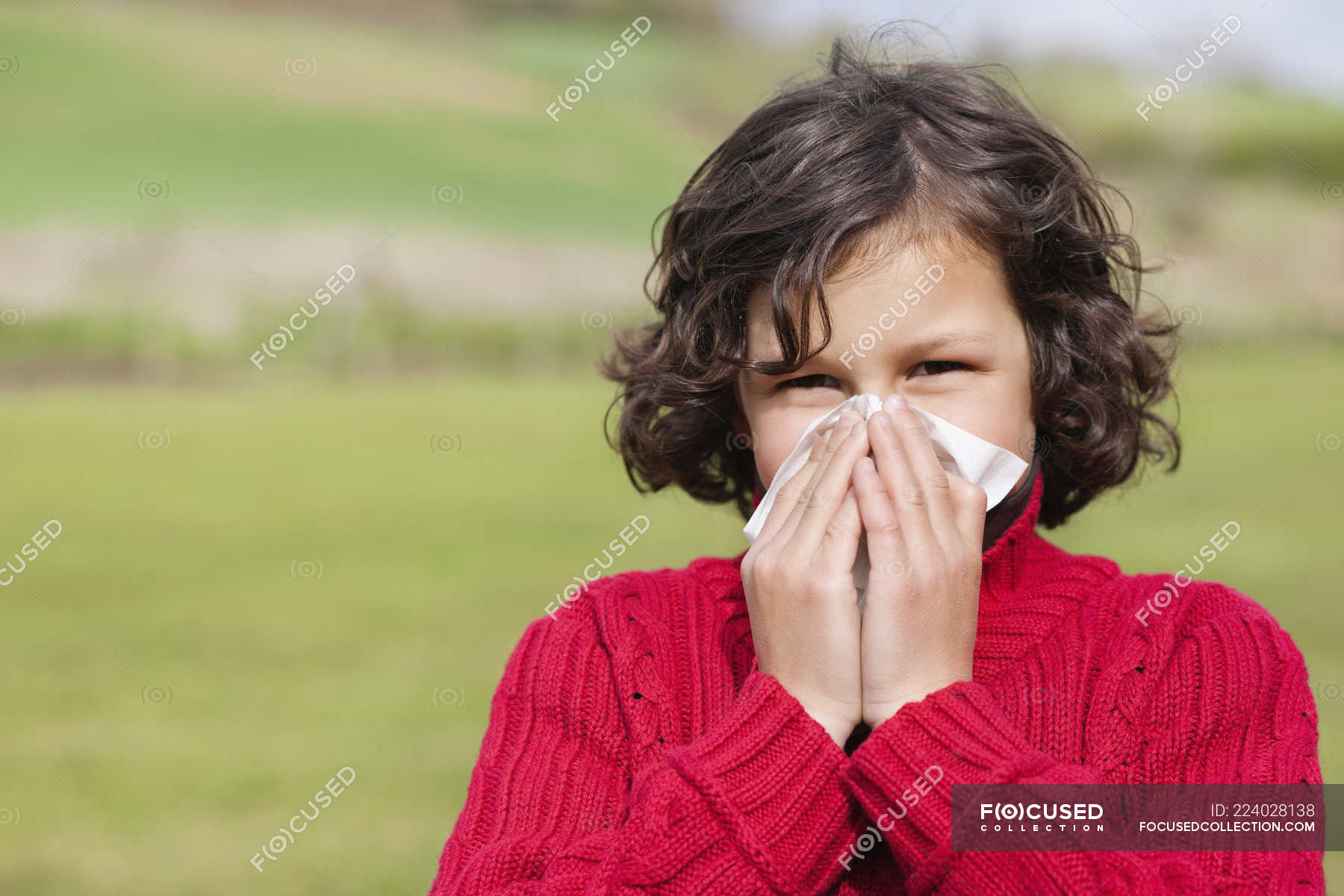 portrait-of-boy-blowing-nose-in-field-people-brown-hair-stock