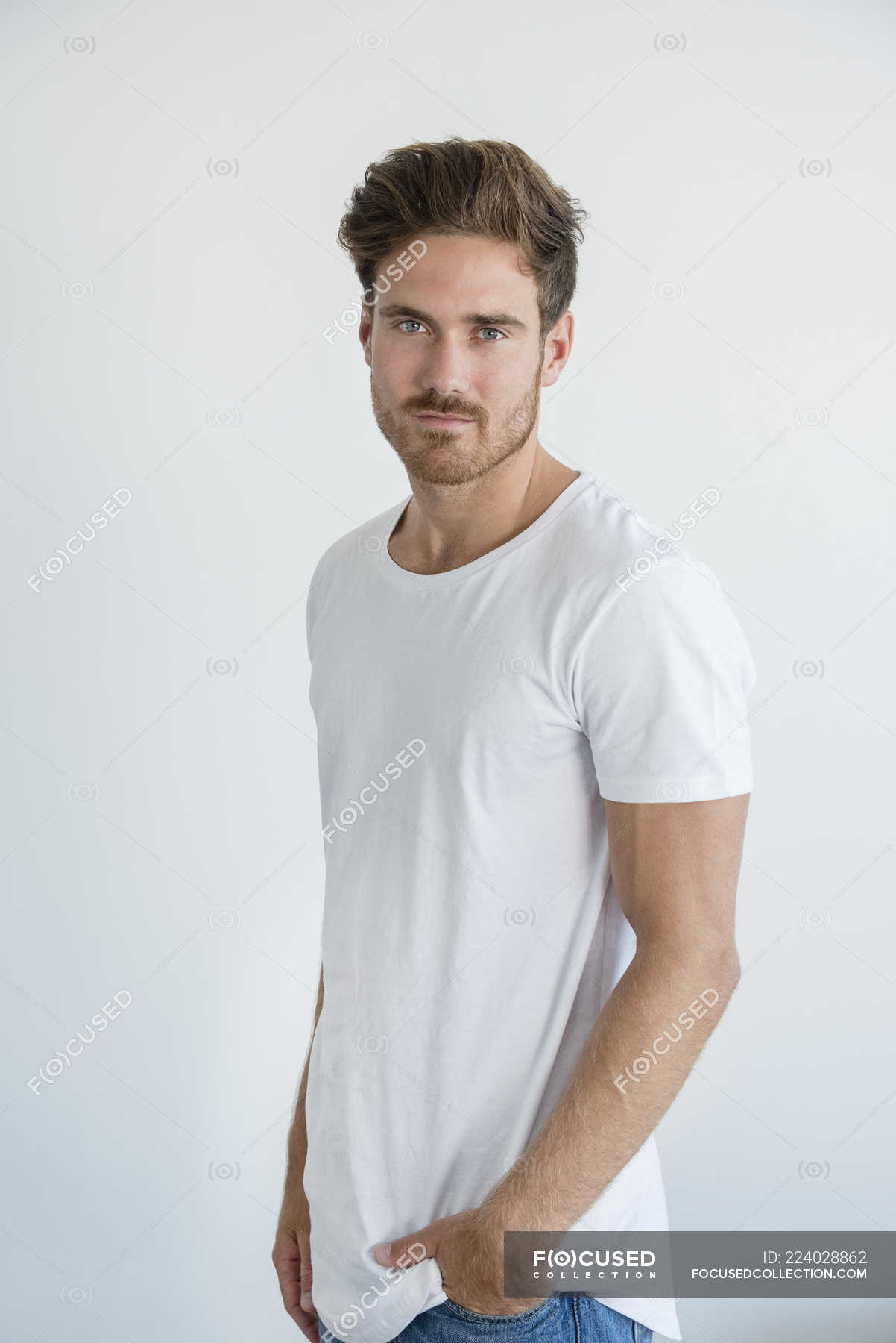 Portrait of handsome young man posing in front of white wall — standing ...