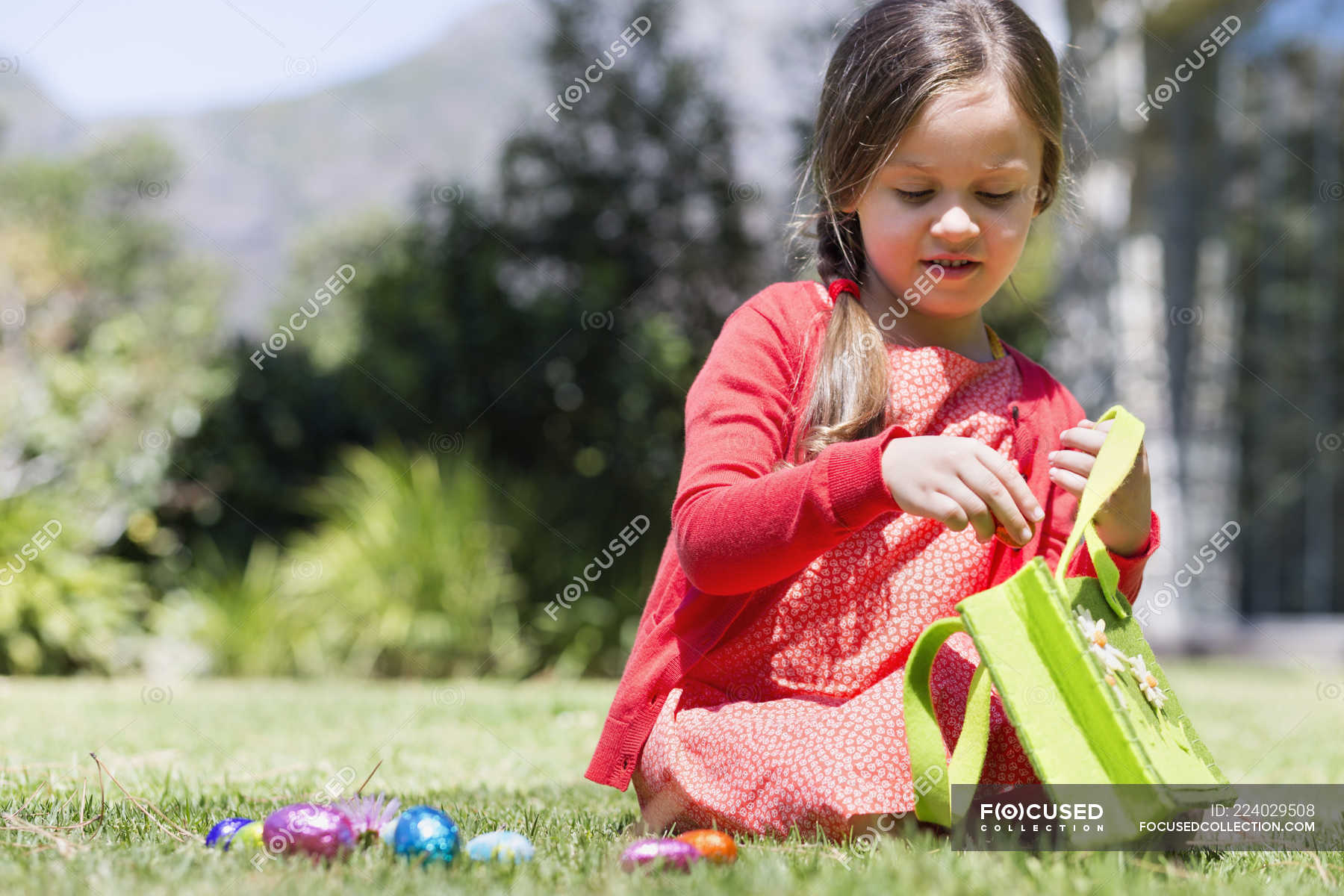 Girl picking up Easter eggs on lawn in nature — spiritual life