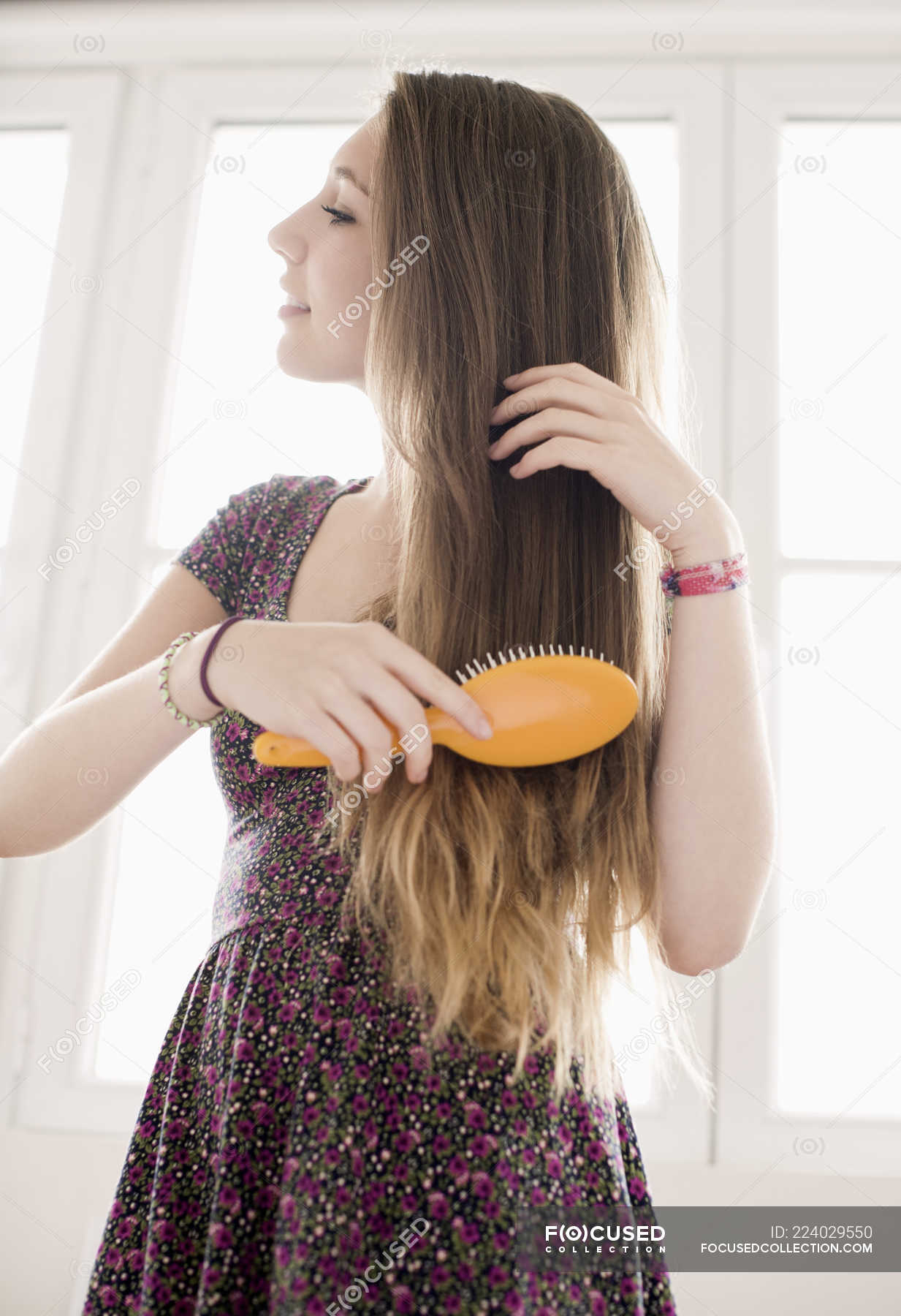 teenage-girl-brushing-hair-in-front-of-window-doing-hair-child