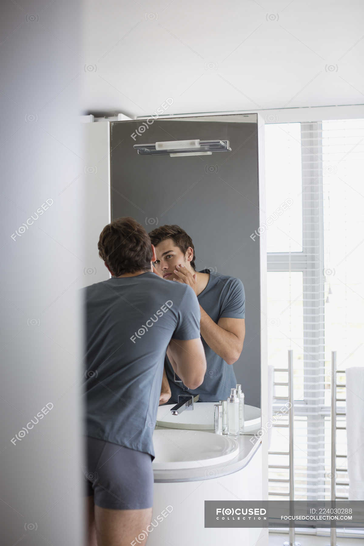 Young checking face in mirror in bathroom — body care, handsome - Stock ...