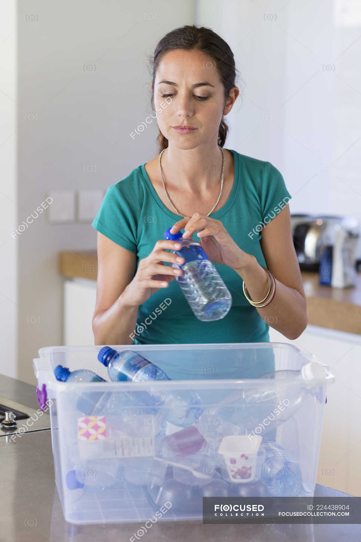 woman-putting-bottle-in-recycling-bin-in-kitchen-household-chores