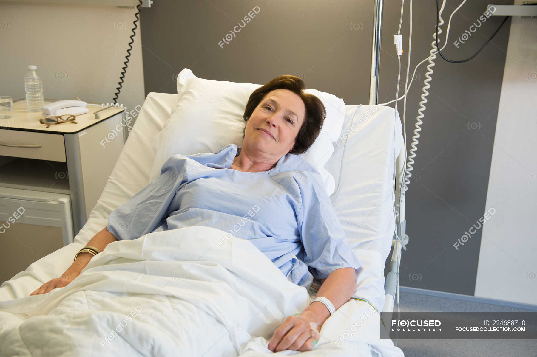 Smiling Mature Woman Lying In Hospital Bed And Looking At Camera — Patient Hospital Gown 