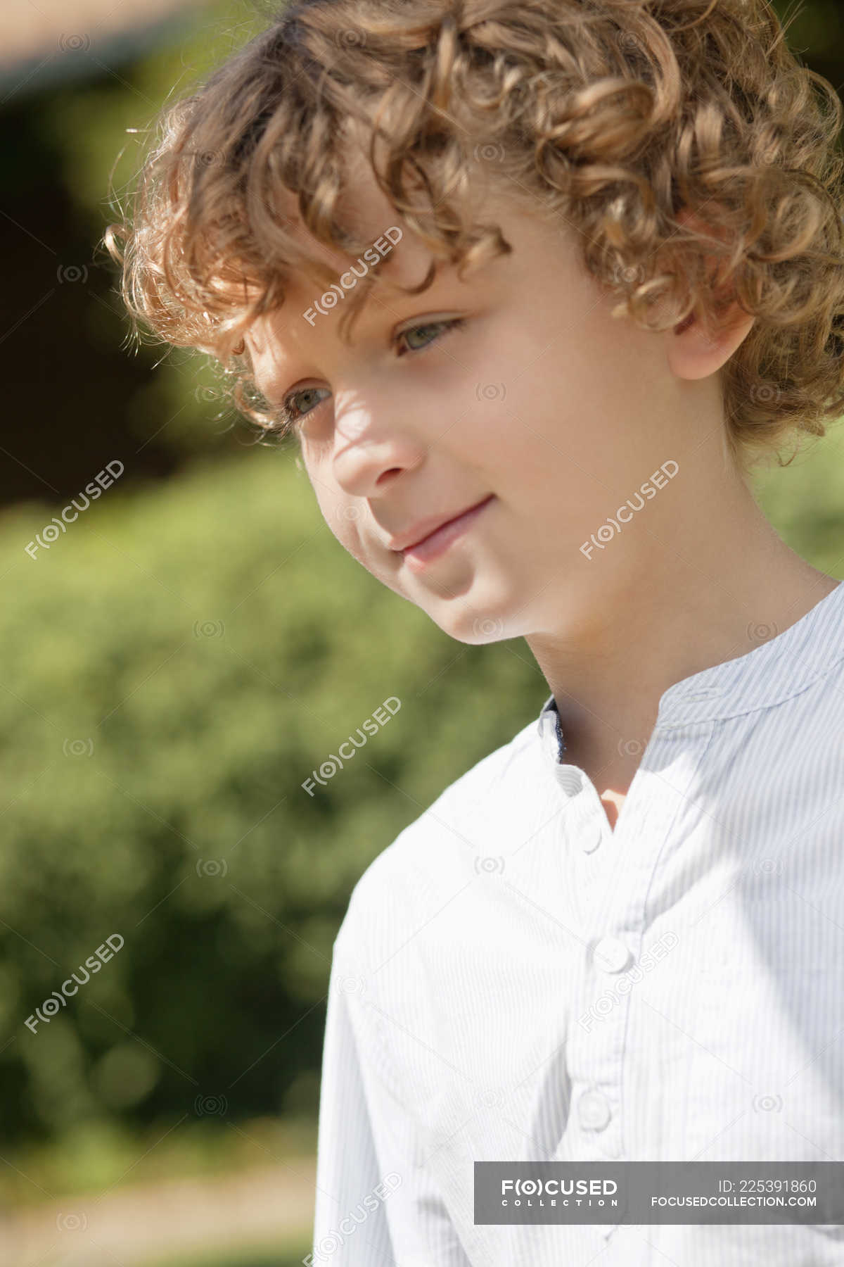 Close-up of smiling boy with curly hair day dreaming in nature — outdoors,  contemplation - Stock Photo | #225391860