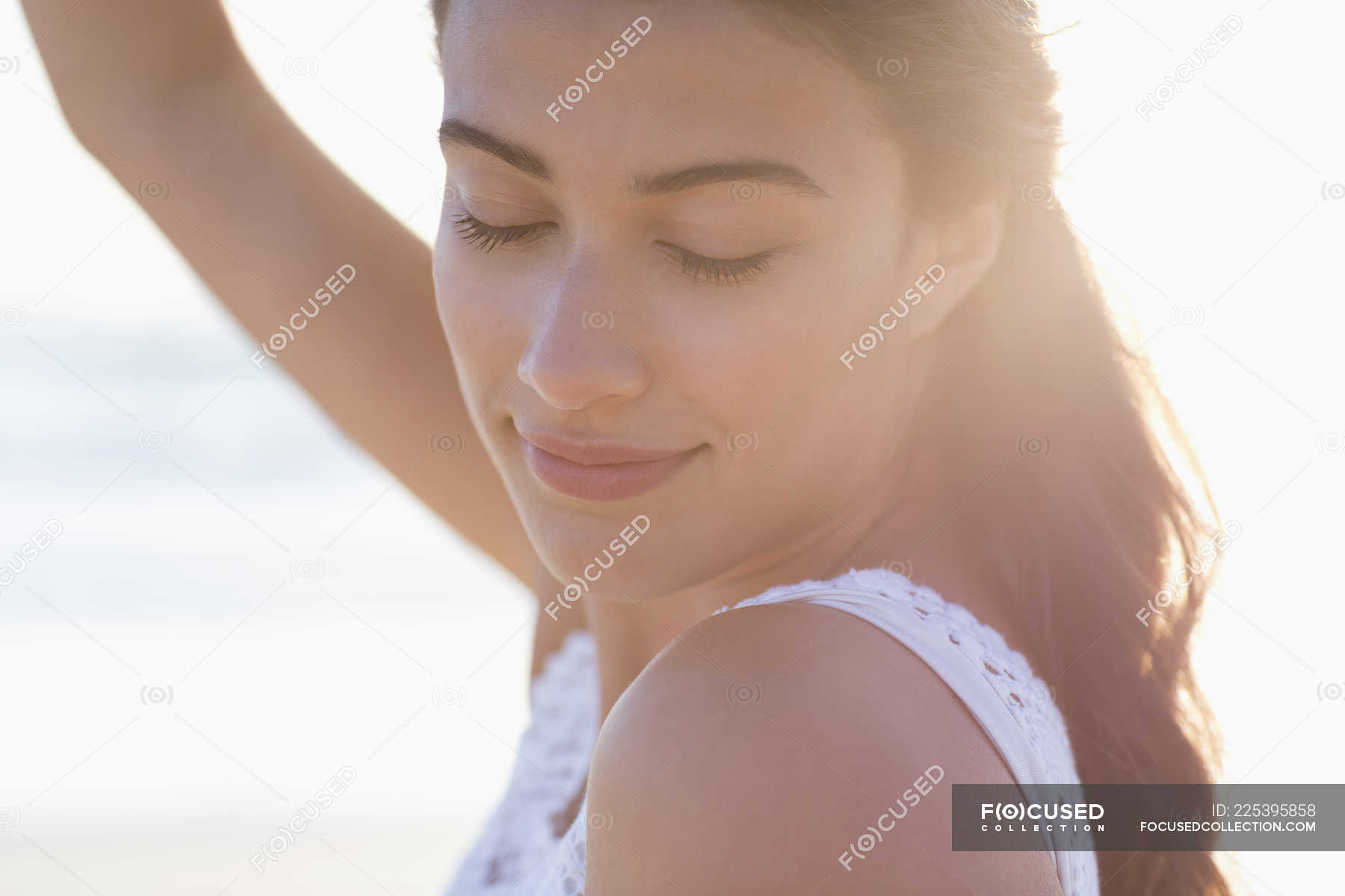 Close-up of thoughtful young woman with eyes closed posing in sunlight ...