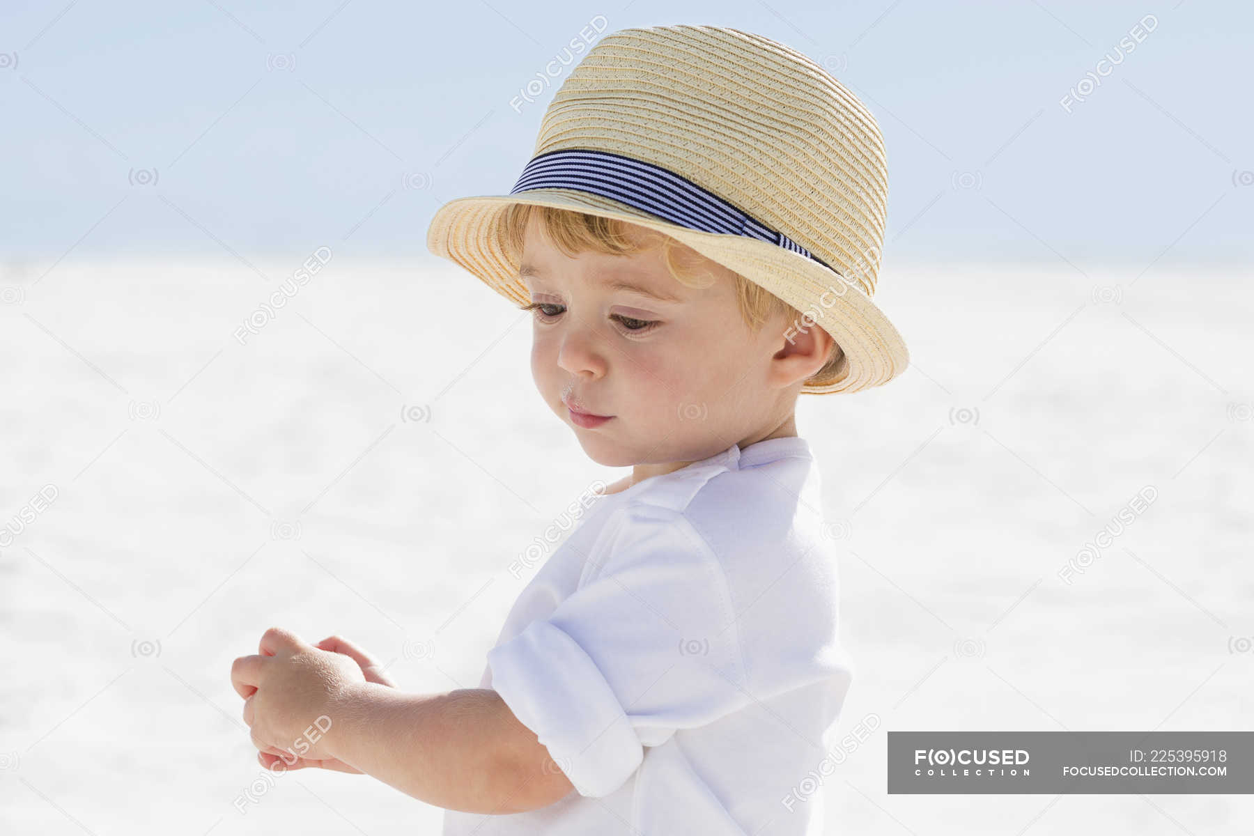 Close-up of cute baby in straw hat playing on beach — profile, innocence - Stock Photo