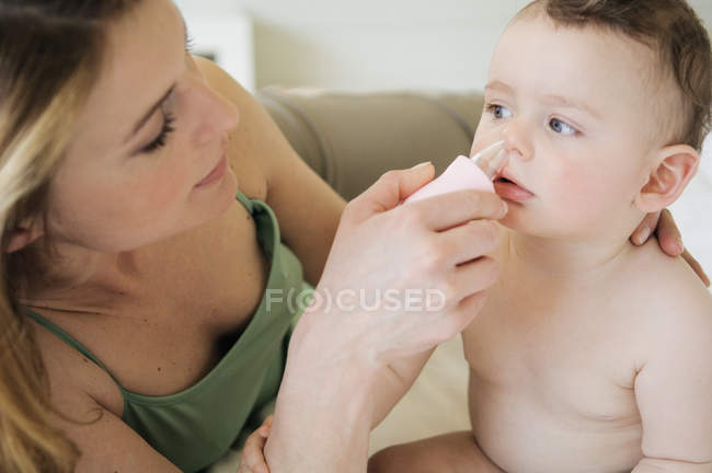 Gros plan de la mère essuyant le nez du bébé — Photo de stock