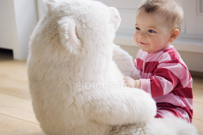 Baby boy playing with teddy bear on floor at home — Stock Photo