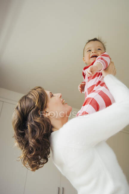 Жінка тримає дитину, посміхаючись — стокове фото