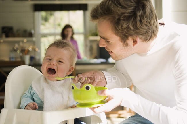 Батько годує свою дитину, плаче — стокове фото