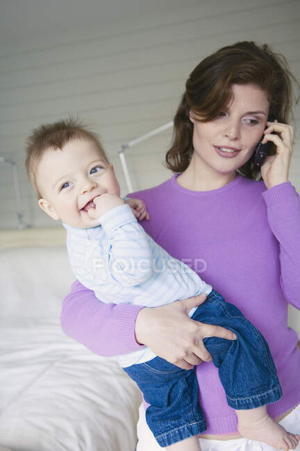Mère tenant son bébé, téléphonant — Photo de stock