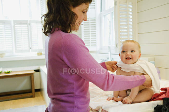 Madre vistiendo a su bebé - foto de stock