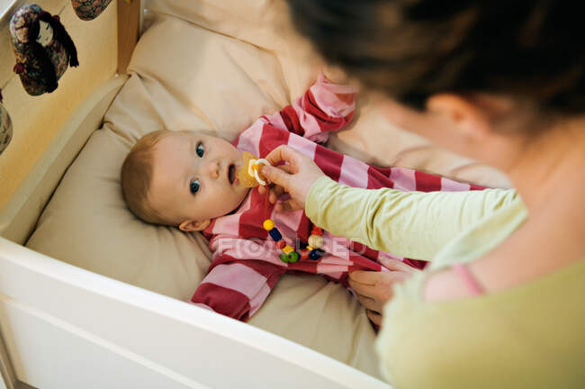 Mère donnant la couette à son bébé au lit — Photo de stock