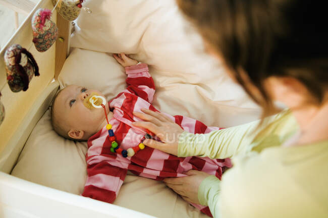 Mutter streichelt ihr Baby im Bett mit Kuscheldecke — Stockfoto