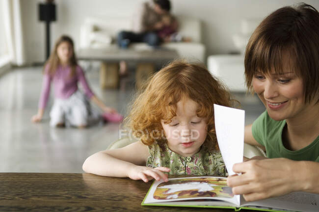 Femme et petite fille lisant un livre pour enfants — Photo de stock