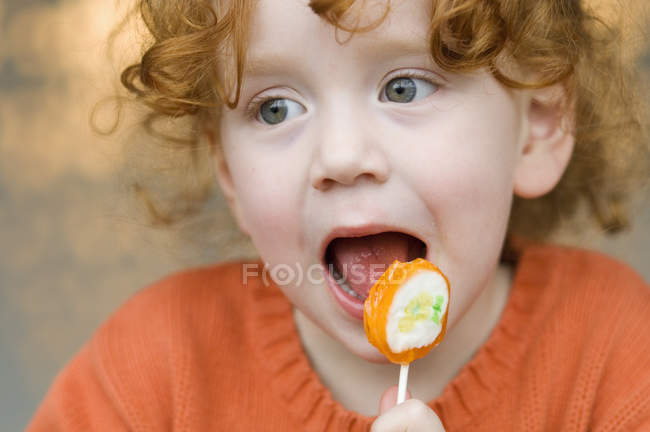 Porträt eines kleinen Mädchens mit Ingwer, das Lutscher isst — Stockfoto