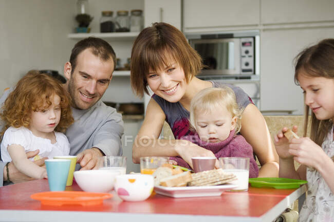 Pareja y 3 niños desayunando - foto de stock