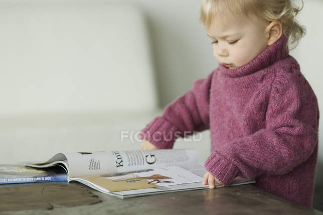 Милый маленький мальчик читает журнал — стоковое фото