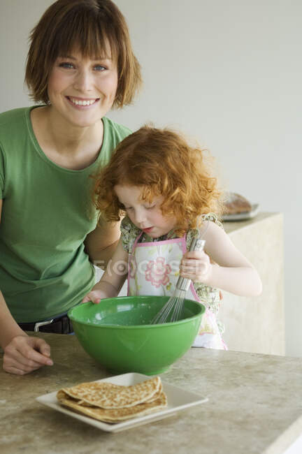 Улыбающаяся женщина и маленькая девочка готовят — стоковое фото