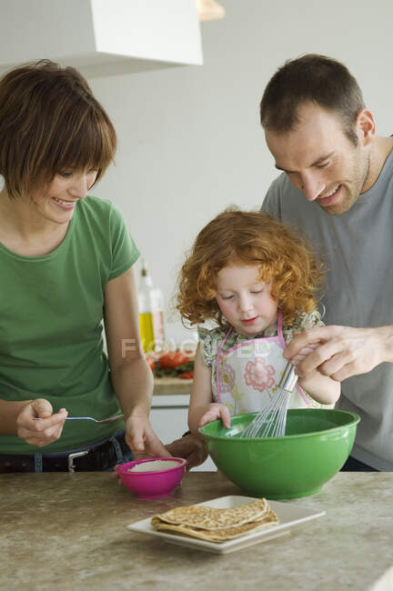 Couple and little girl cooking — Stock Photo