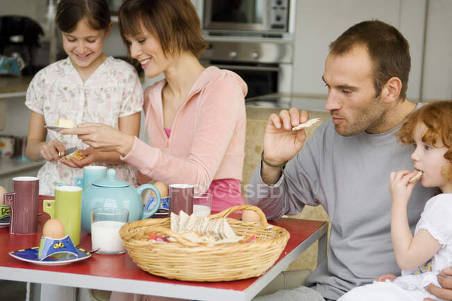 Pareja y 2 niñas en la mesa del desayuno - foto de stock