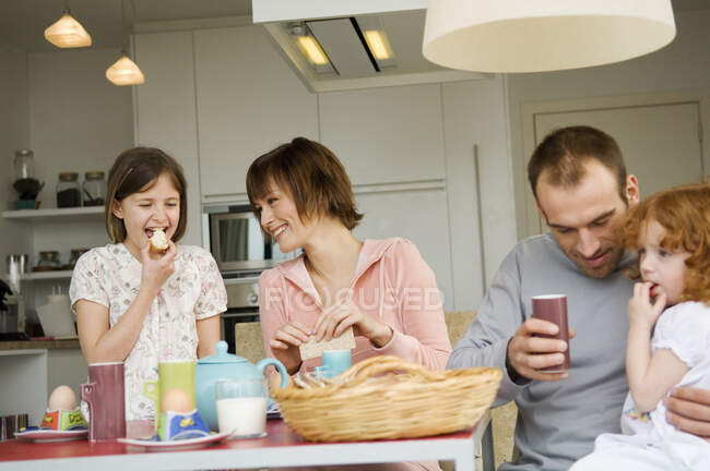 Pareja y 2 niñas en la mesa del desayuno - foto de stock