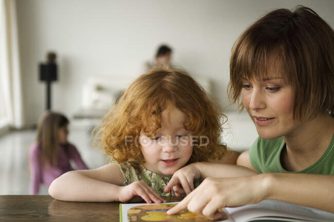 Маленька дівчинка і жінка читають дитячу книгу — стокове фото