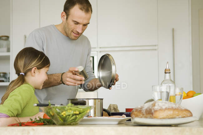 Hombre y niña cocinando en la cocina doméstica - foto de stock