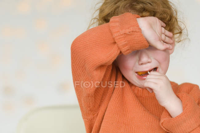 Portrait of ginger little girl crying with arm over eyes — Stock Photo