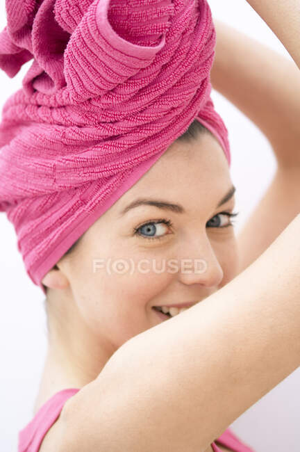 Porträt einer jungen Frau, die in die Kamera blickt, rosafarbenes Handtuch auf dem Kopf — Stockfoto