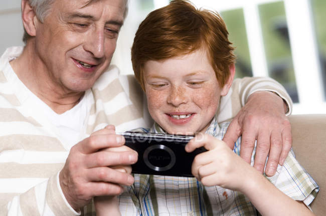 Мужчина и мальчик играют в Playstation Portable — стоковое фото