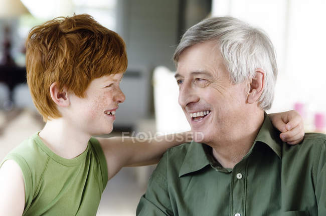 Хлопчик обіймає дідуся, дивлячись один на одного — стокове фото
