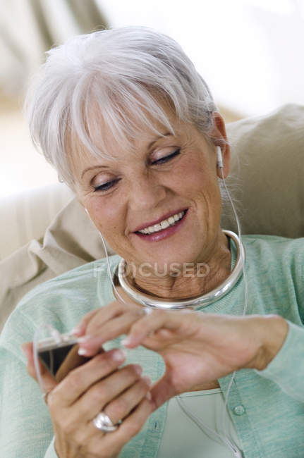 Портрет счастливой пожилой женщины, слушающей MP3-плеер — стоковое фото