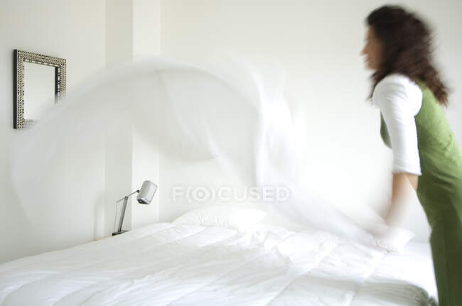 Женщина застилает постель — стоковое фото