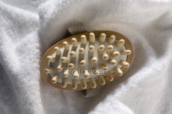 Nahaufnahme eines hölzernen Massagegeräts auf weißem Badetuch — Stockfoto